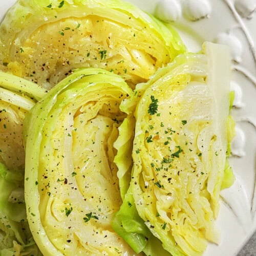 boiled cabbage wedges on a white serving platter