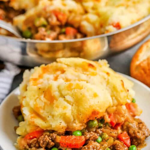 a serving of cottage pie in a bowl with panful of cottage pie in the background