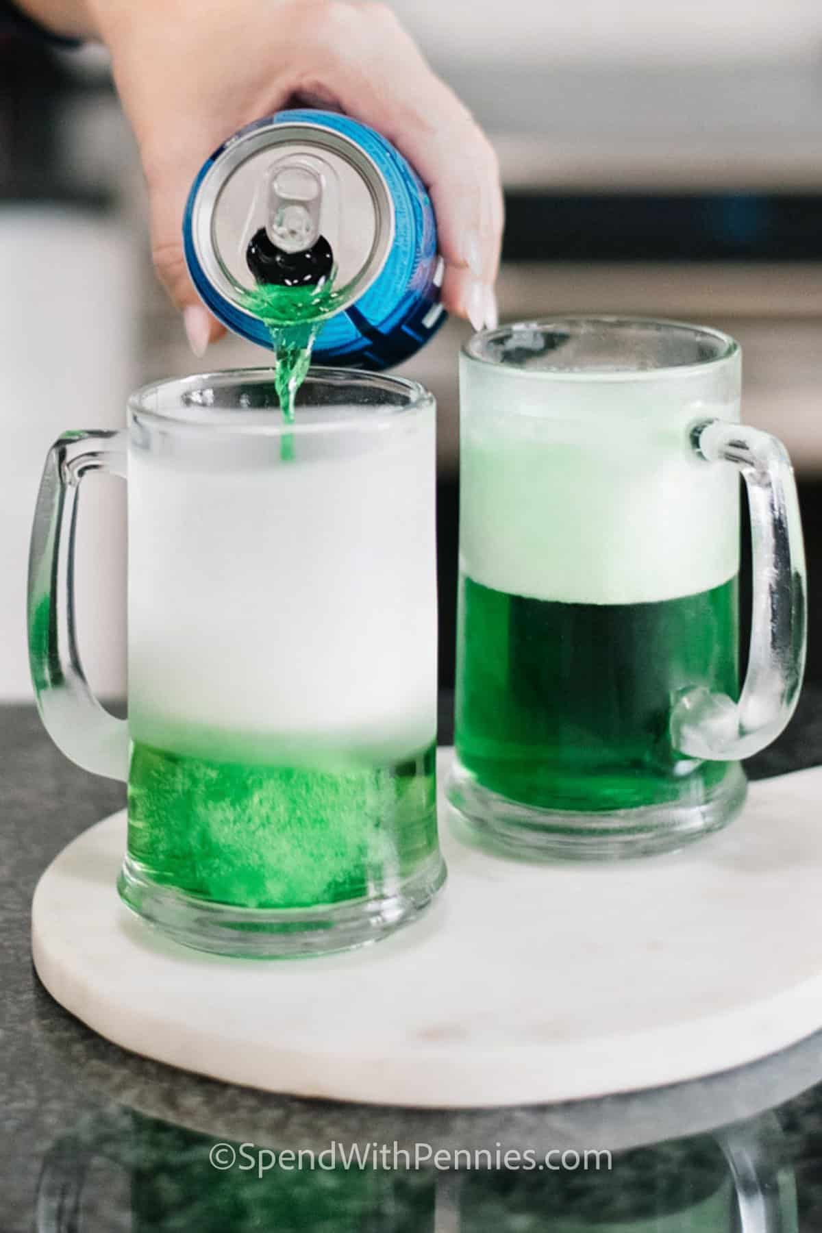 adding beer to top off glasses of green beer on a white platter