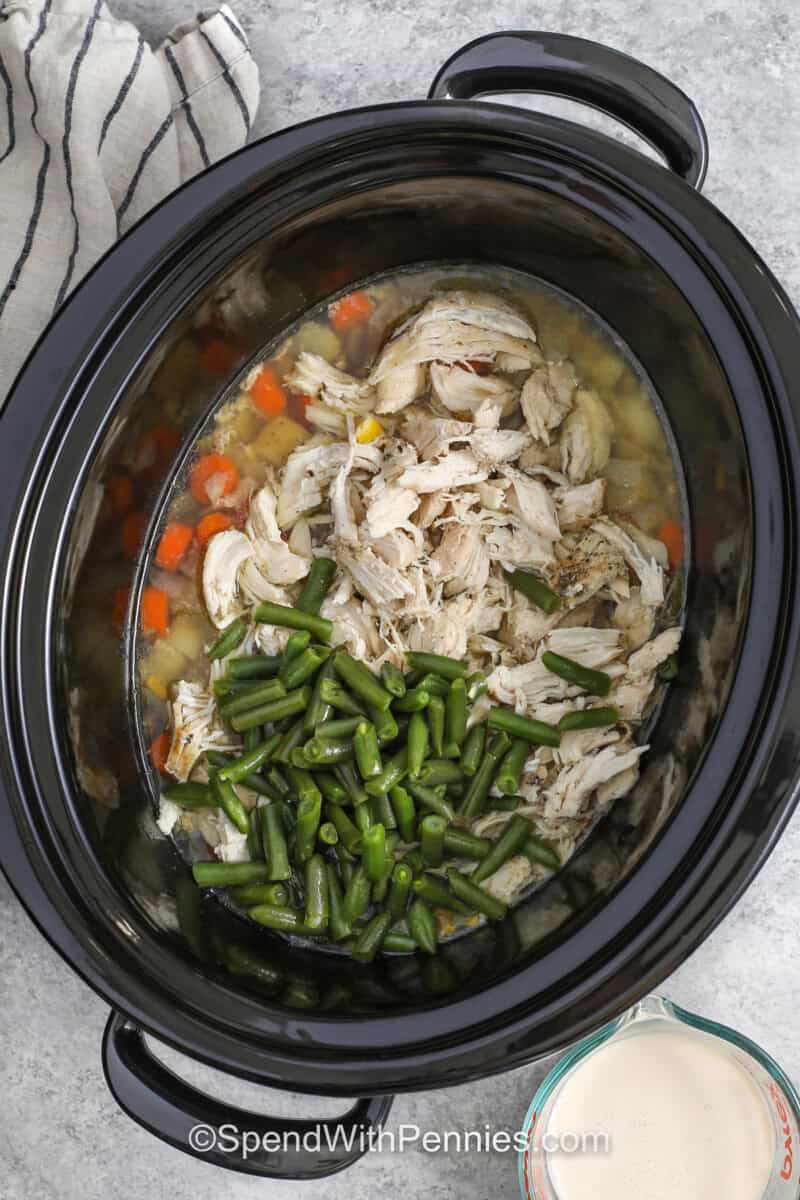 adding cooked chicken and green beans to pot to make Slow Cooker Chicken Stew