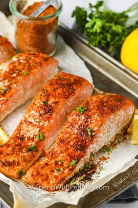 salmon cooked on a sheet pan with a jar of Salmon Seasoning