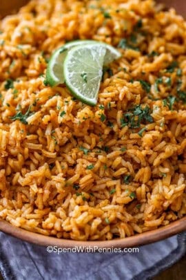 A close up of Mexican rice recipe in a bowl with lime slices.