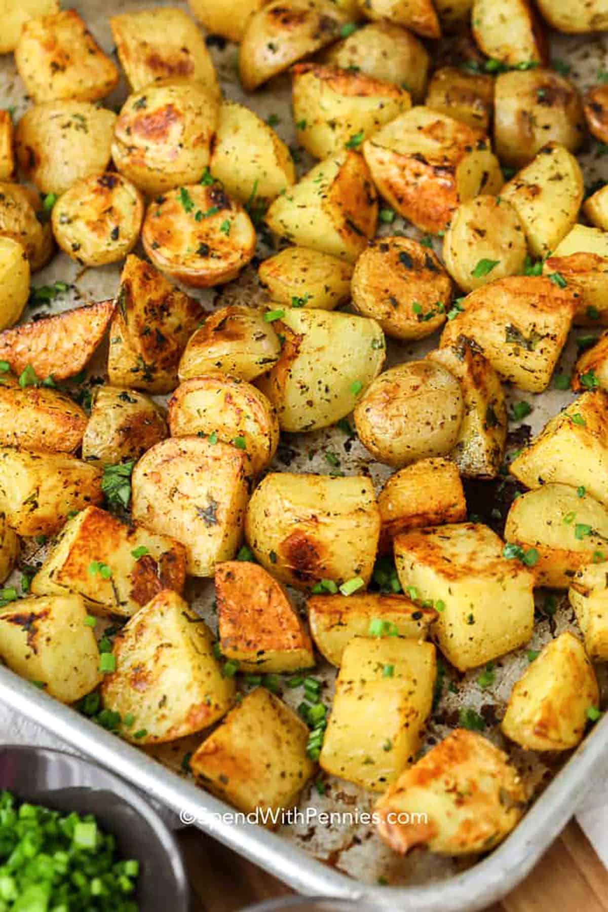 Oven roasted potatoes are the perfect easy side dish with crisp golden edges and tender centers. Made with red, yellow, or Yukon gold potatoes, they’re tossed in olive oil, garlic powder, paprika, and fresh herbs. Roasted at high heat, they come out fluffy inside and perfectly seasoned every time. Serve them with any meal from breakfast to dinner! #spendwithpennies oven roasted potatoes in a metal pan