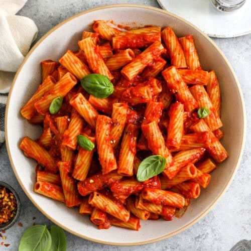 top view of rigatoni arrabbiata in a white serving bowl with parmesan
