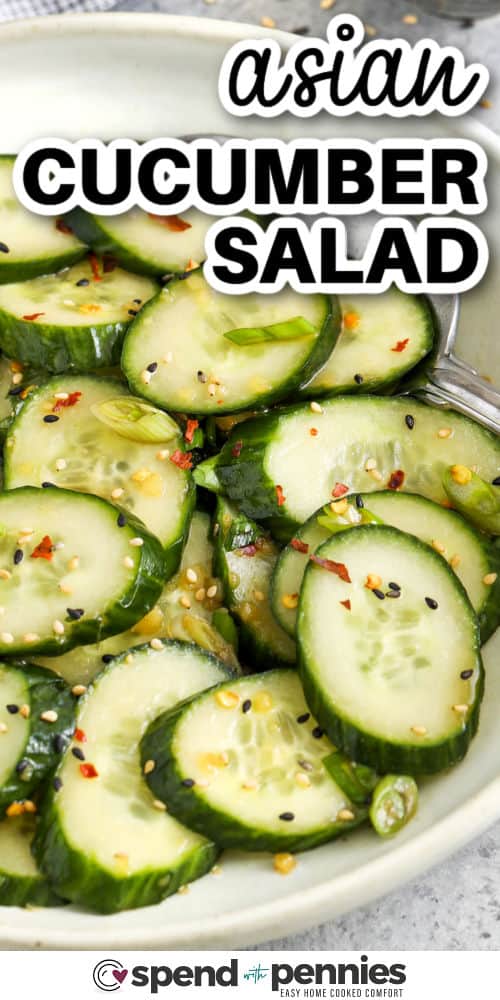 asian cucumber salad in a white serving bowl with a spoon and writing