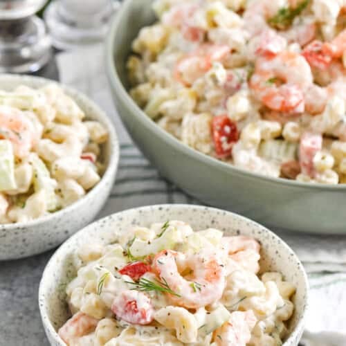 shrimp pasta salad in a green serving bowl and two bowls