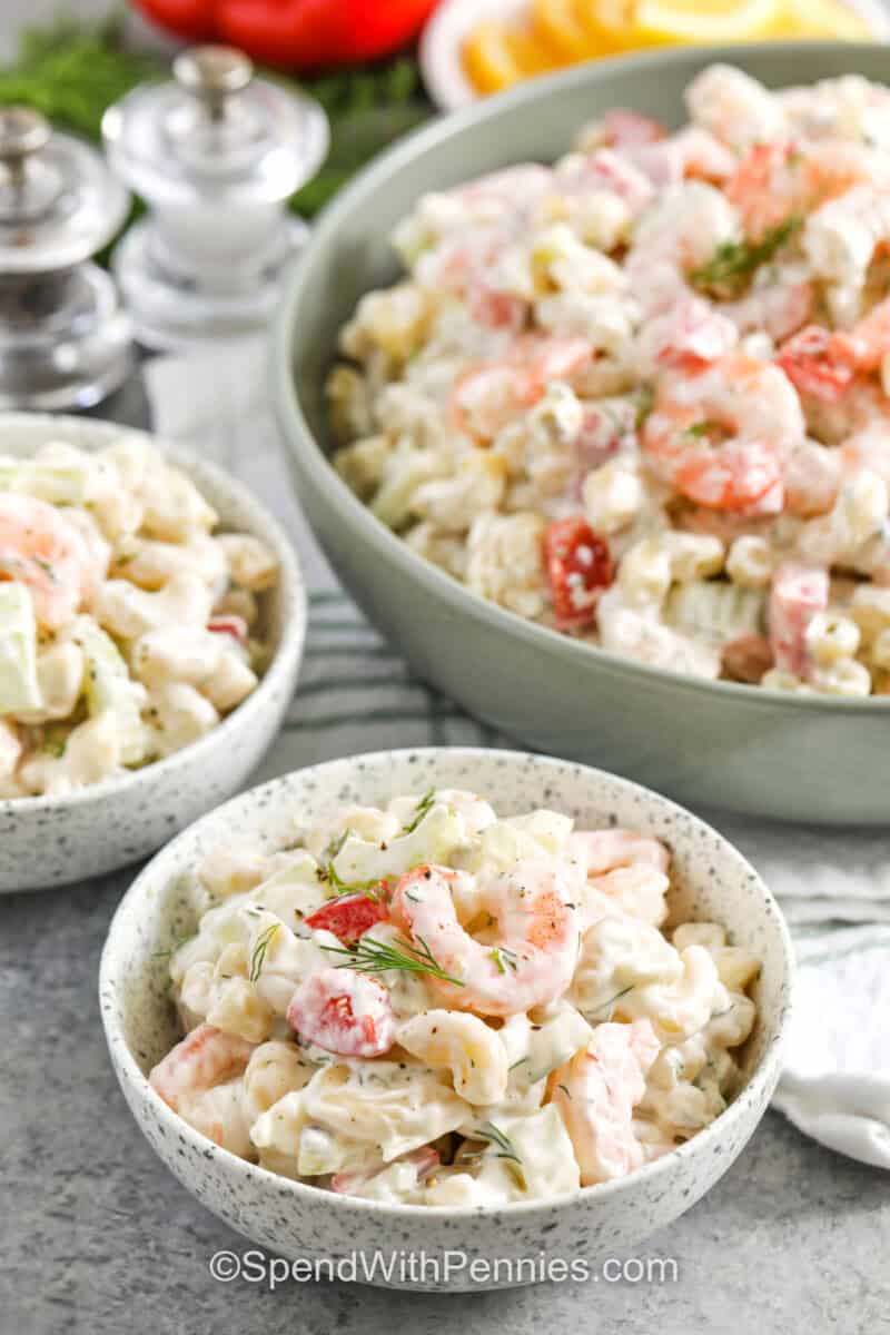 shrimp pasta salad in a green serving bowl and two bowls