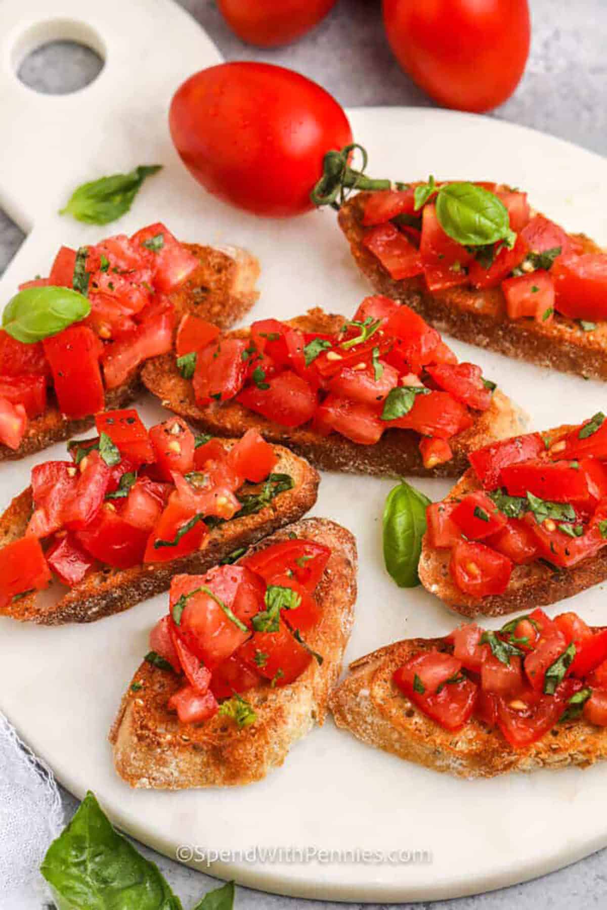 Bruschetta makes the best appetizer or snack and it can be customized, too. Try making this classic tomato recipe and add some chopped or sliced chicken, fresh mozzarella, goat cheese, fresh basil, and a balsamic glaze. Don't forget the crispy baguette bread. Bruschetta can also be added to pasta or sauce for a whole new recipe! #bruschetta #tomatobruschetta #appetizer #spendwithpennies classic Bruschetta on bread