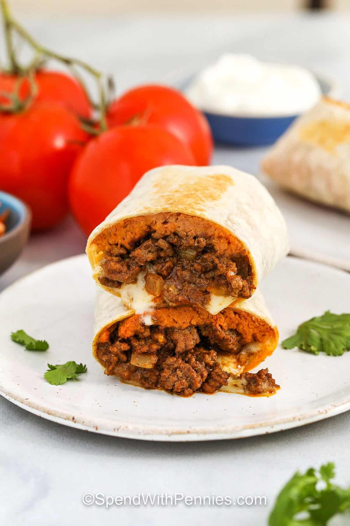 This favorite beef burrito recipe is a hearty, comforting meal that’s easy enough for a weeknight but tasty enough to serve to guests. Ground beef is browned with onions, tossed with taco seasoning, and folded into warm tortillas with refried beans and cheese. Cilantro adds a touch of freshness, and pan-toasting adds a crisp bite. Great for making ahead or feeding a crowd, these burritos are full of flavor and sure to satisfy! #spendwithpennies plated Beef Burrito Recipe