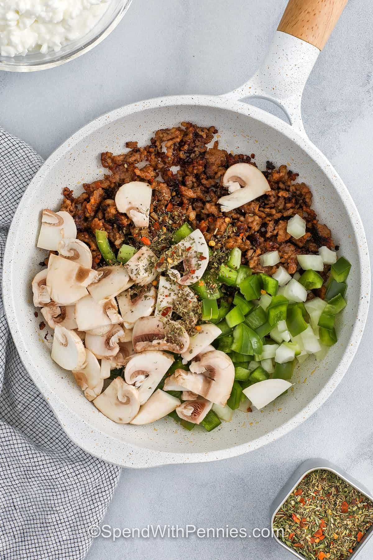 A cottage cheese pizza bowl is the perfect way to enjoy pizza night with a fun and creamy twist. The cottage cheese mixture bakes up rich and flavorful, kind of like a pizza lasagna without the noodles. Add in browned sausage, peppers, mushrooms, and your favorite sauce for a hearty layer of flavor. Topped with mozzarella, Parmesan, and pepperoni, it’s gooey and golden. It’s a great way to use what’s in your fridge. Everyone will ask for seconds. #spendwithpennies adding vegetables to cooked italian sausage to make Cottage Cheese Pizza Bowls