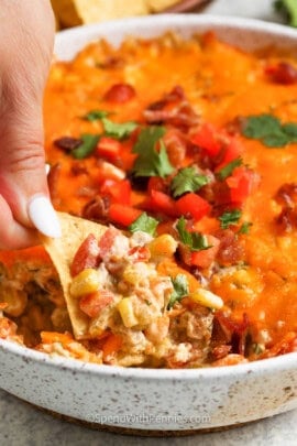 dipping a chip in Creamy Baked Corn Dip