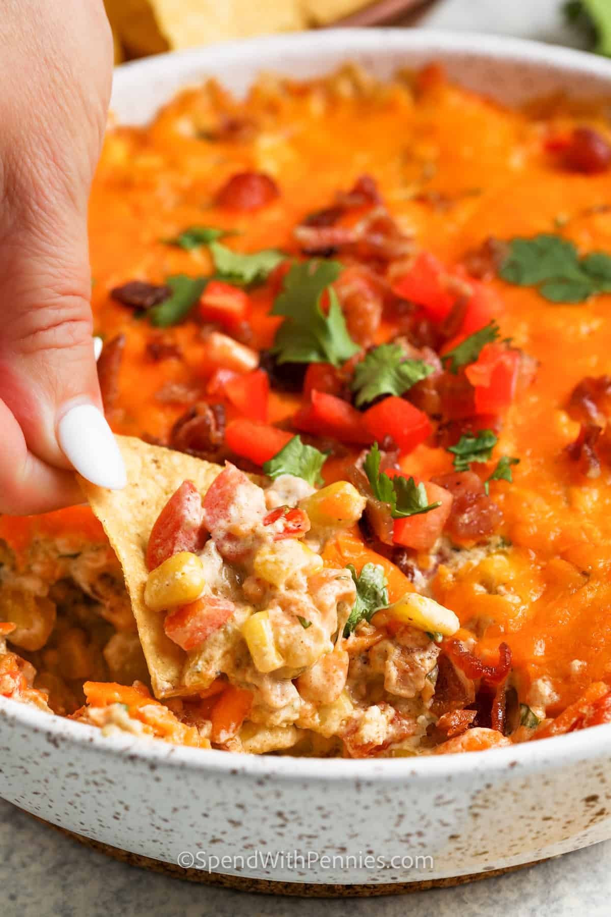 dipping a chip in Creamy Baked Corn Dip