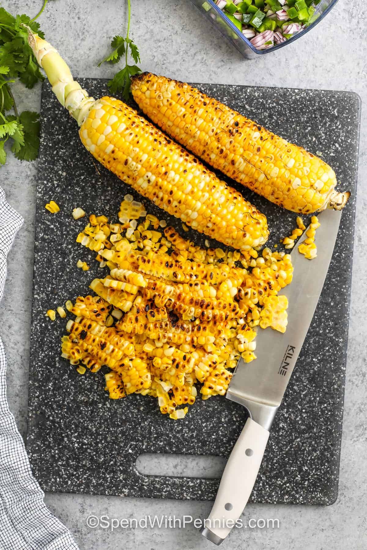 cutting corn off the cob to make Elote Pasta Salad