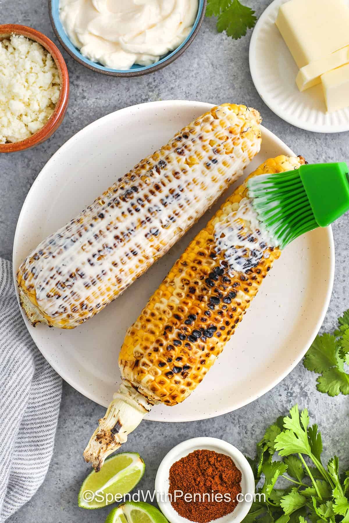 brushing sour cream mixture over corn on the cobs to make Mexican Street Corn