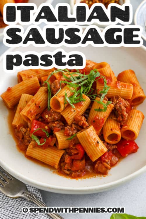 Italian sausage pasta is bold, hearty and full of flavor and the whole family will love it. Juicy sausage, tender pasta and fire-roasted red peppers gather together. A simple tomato-based sauce tie them together every time to make it a perfect bite. Add a bunch of parmesan cheese and some fresh basil to dinner, just like your favorite Trattoria. Comfortable food becomes easy and always takes a hit. #spendwithpennies Close-up of Italian sausage pasta with title