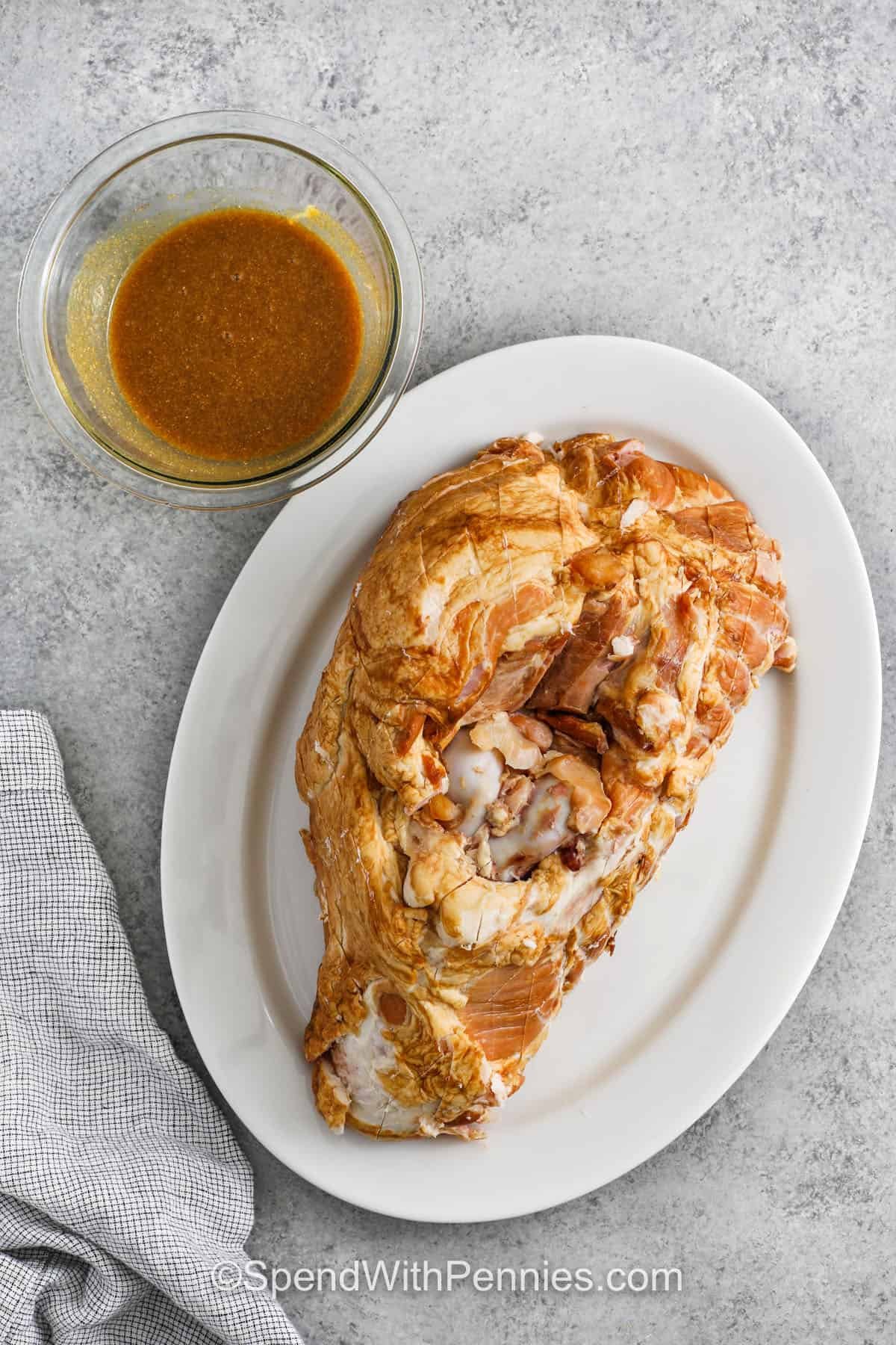 ham on a plate with sauce in a bowl