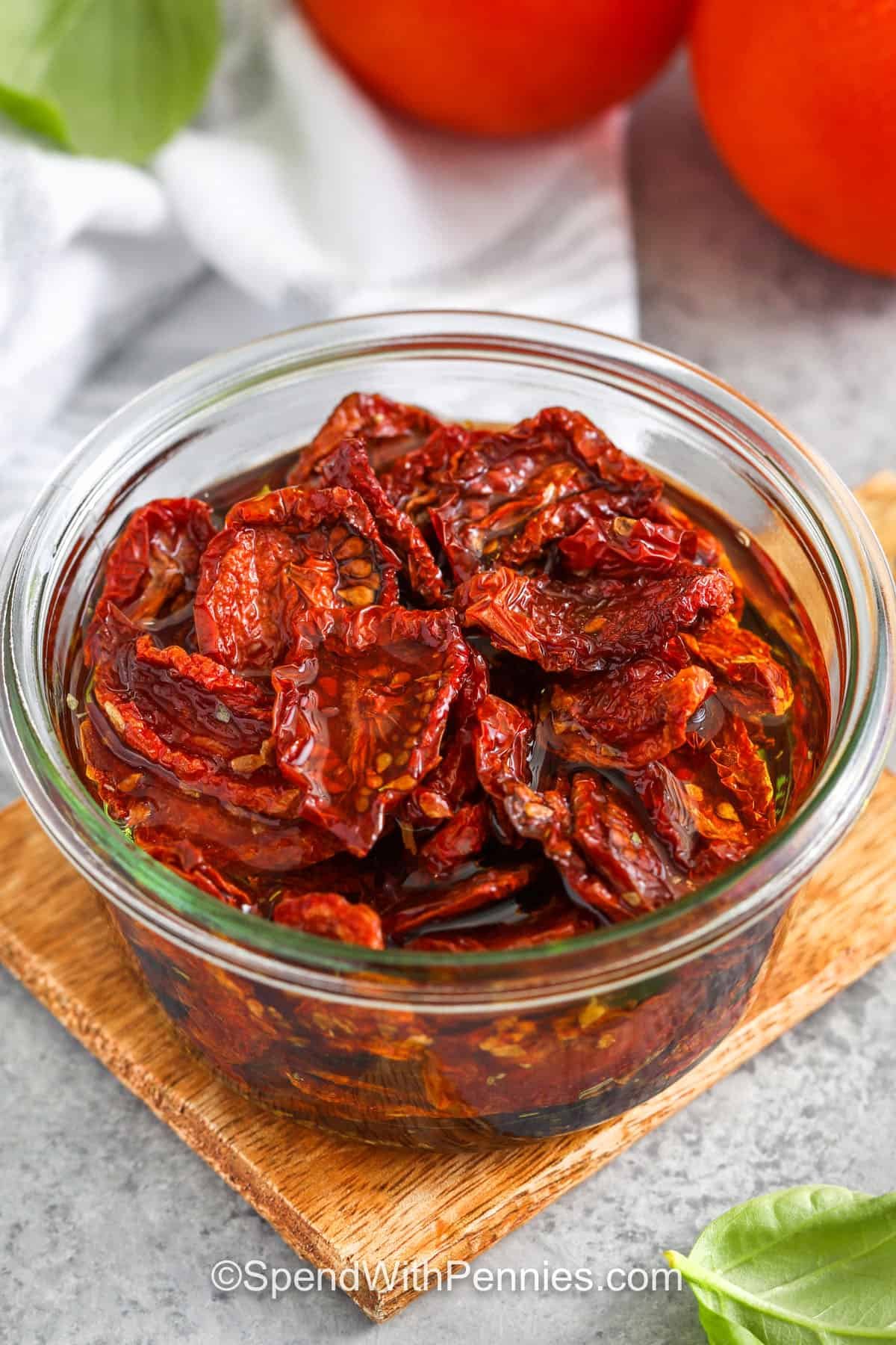 These homemade sun dried tomatoes are a flavorful way to use up fresh tomatoes and take minimal effort to prepare. Roasting low and slow concentrates the flavor and creates a deliciously chewy bite. Add olive oil and herbs to boost flavor and store them for weeks. Use them in omelets, salads, or on homemade pizzas for a burst of tomato goodness in every bite! A must-have for tomato lovers. #spendwithpennies bowl of Sun Dried Tomatoes