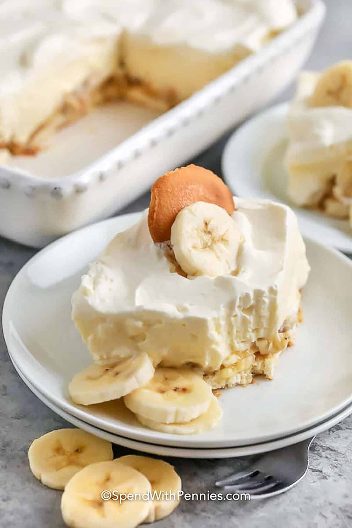 Banana pudding is the kind of simple dessert that makes every meal feel extra special. It’s made with whipped topping, pudding, vanilla wafers, and of course, lots of bananas. The flavors soak into the layers just right, making every spoonful taste like a creamy dream. Make it ahead or enjoy it right away; either way, it’ll be the first thing gone from the table. It’s a keeper for sure. #spendwithpennies slice of Banana Pudding Recipe on a plate with a bite taken out
