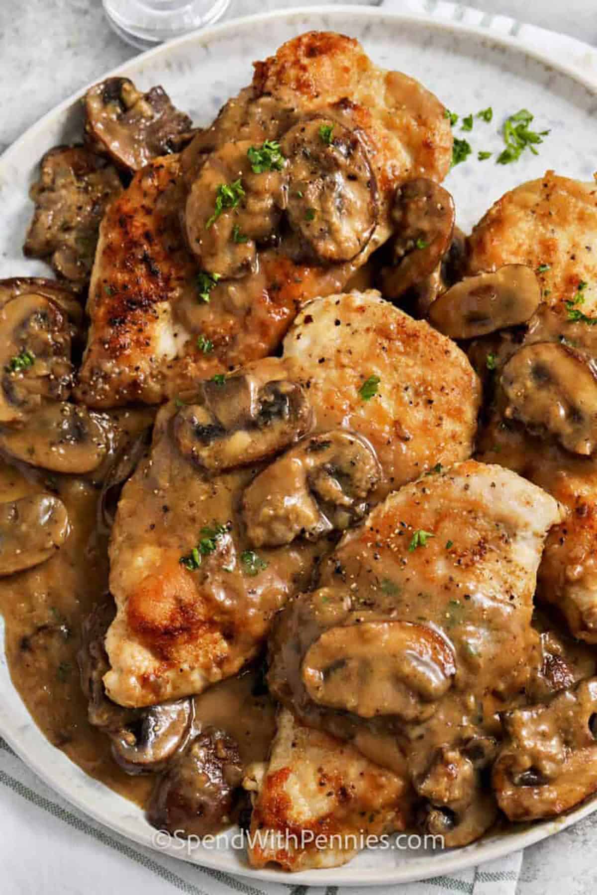 Chicken Marsala is a restaurant-style dish made at home with tender chicken breasts lightly floured and pan-fried until golden, then simmered in a rich mushroom and Marsala wine sauce. The sauce is savory, slightly sweet, and full of umami flavor from the mushrooms and shallots. Serve it over pasta or mashed potatoes to soak up every drop of the delicious sauce. #spendwithpennies close up of plated Chicken Marsala