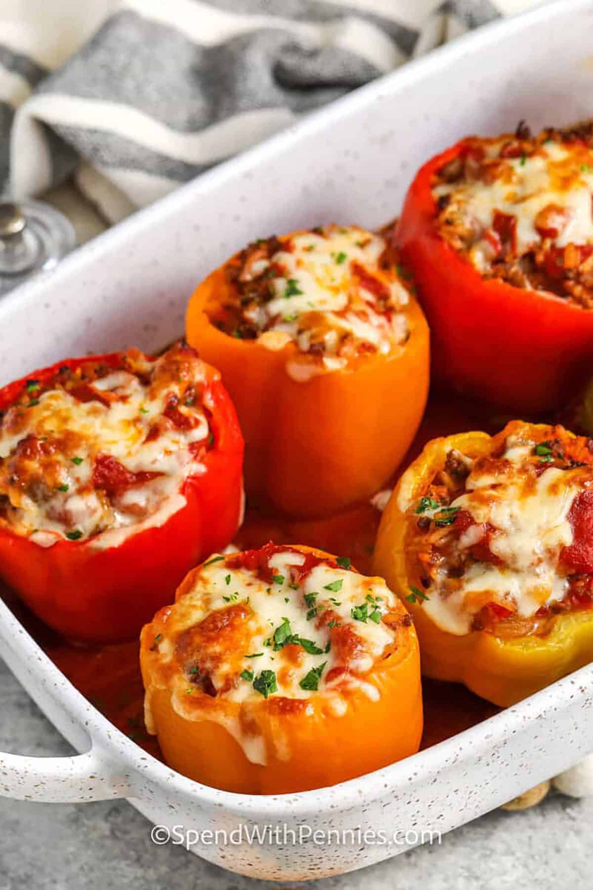 Stuffed peppers make the perfect hearty, flavor-packed dinner! These colorful peppers are filled with a savory blend of sausage, beef, and rice, then baked with a layer of gooey melted cheese. This recipe is simple to make, great for meal prep, and freezes beautifully, so it’s easy to enjoy anytime. Serve up these stuffed peppers with your favorite sides for a complete meal that everyone will love! #spendwithpennies dish of Stuffed Peppers