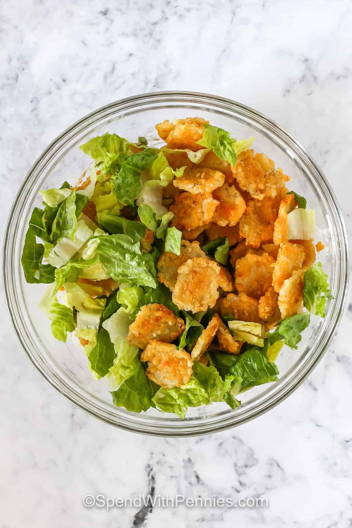 adding tater tots to lettuce to make Crispy Tater Caesar Salad