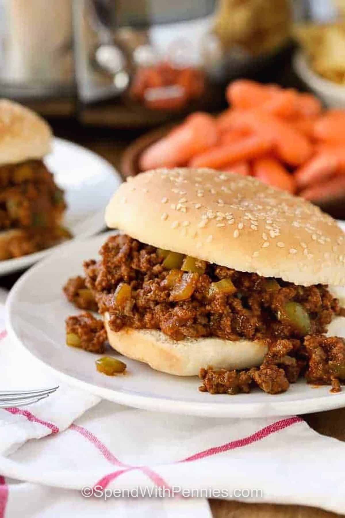 Crock Pot Sloppy Joes on plates with crock pot in the back