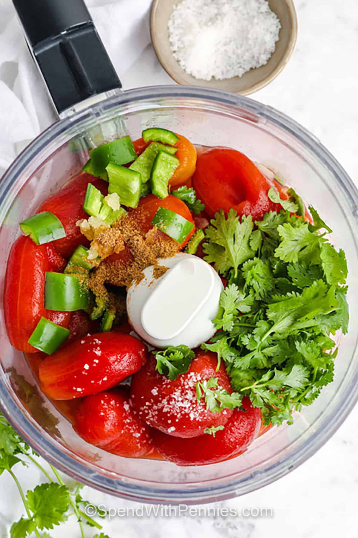 Homemade salsa is the perfect way to add a pop of flavor to chips, tacos, and more. Made with canned tomatoes and fresh ingredients like lime, garlic, and cilantro, it blends up in seconds and tastes like it came from a restaurant. Adjust the spice by adding more jalapeño or keep it mild. Either way, it’s sure to be a favorite at any gathering. #spendwithpennies adding ingredients to food processor to make Homemade Salsa