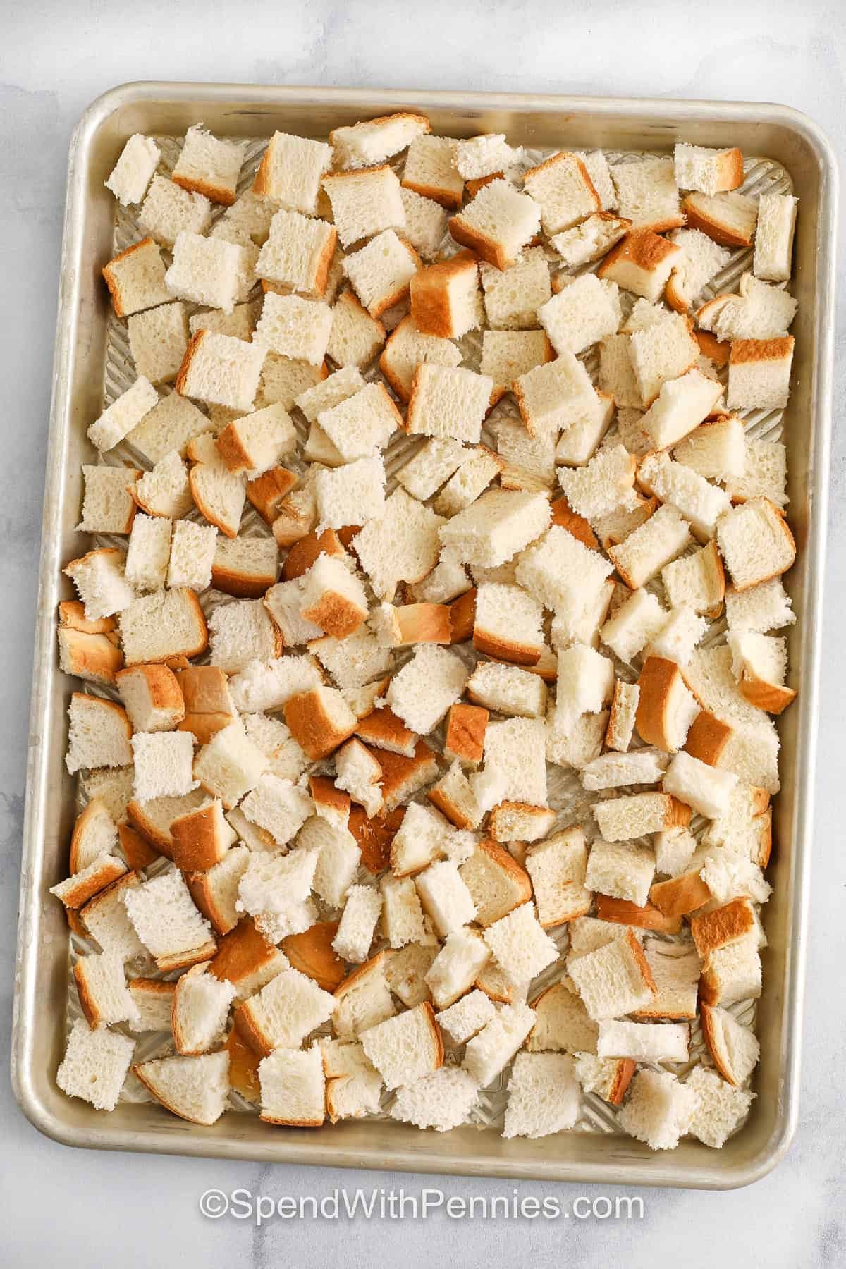 Make seasoned bread crumbs from scratch using your own oven-dry bread for a fresher, more flavorful result than store-bought. Whether you choose panko or plain, both bring great texture. With just a few herbs and spices, these crumbs turn ordinary meals into something special. Sprinkle over veggies, use as a binder in meatloaf, or coat chicken for a crisp finish. So versatile and budget-friendly! #spendwithpennies bread pieces on a sheet pan to make Seasoned Bread Crumbs