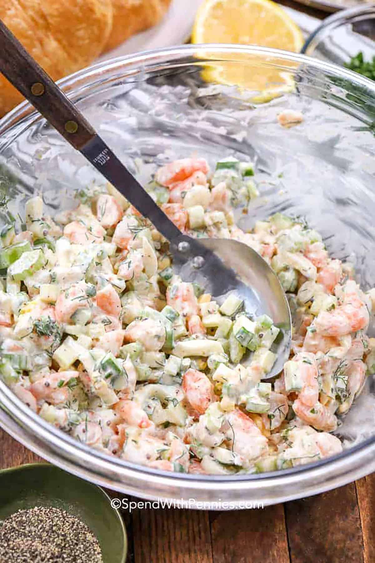 This shrimp salad recipe is creamy, cool, and packed with bright, fresh flavors. Shrimp, crunchy celery, cucumber, and eggs come together with dill and a touch of mustard for a salad that’s both simple and satisfying. Scoop it onto a croissant or enjoy it with lettuce or chips for a quick meal. It’s perfect for lunch, brunch, or any time you’re craving something light and tasty. #spendwithpennies mixed Shrimp Salad ingredients in a glass bowl