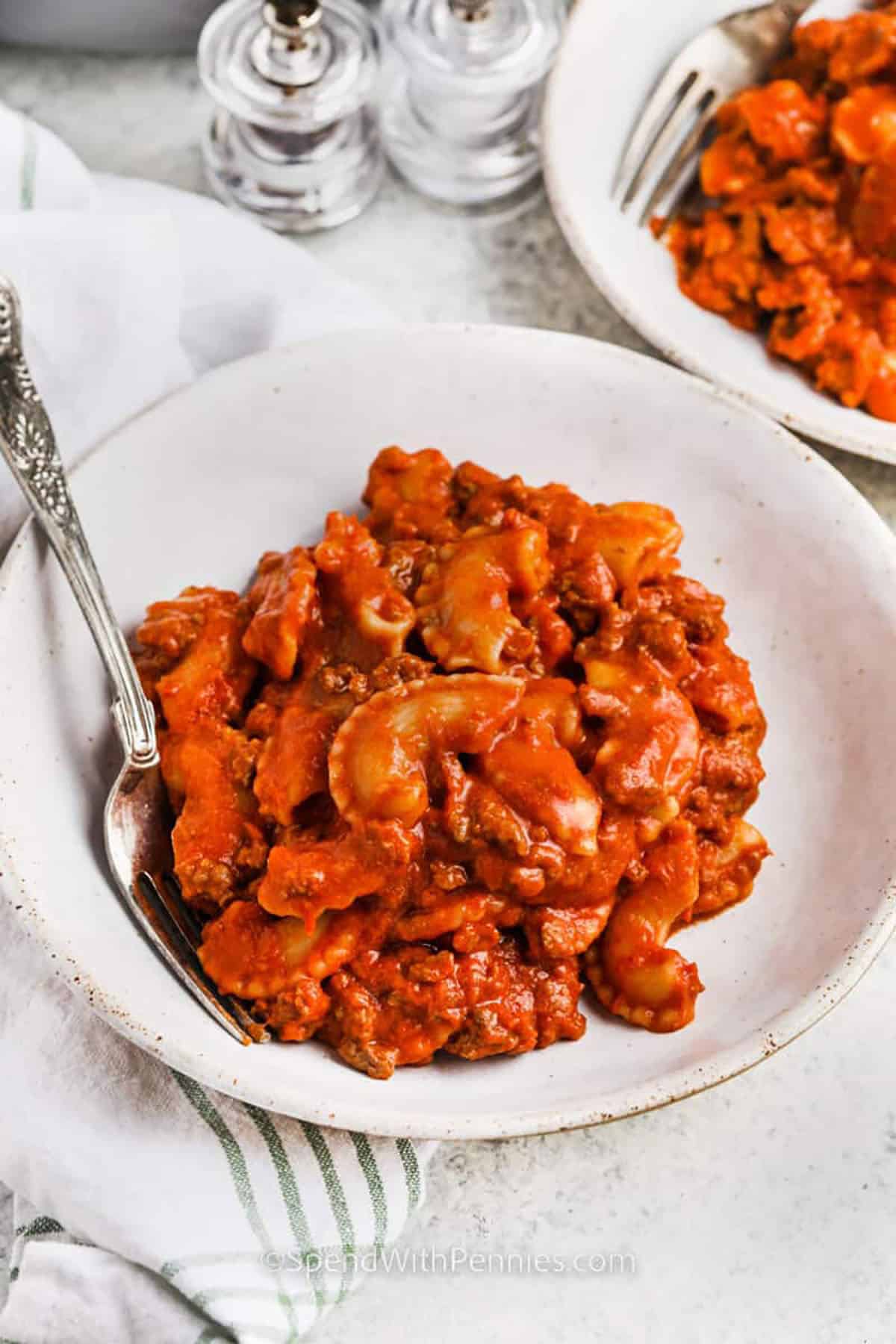 This beefaroni recipe makes the best stovetop pasta dinner. Everything is made from scratch in one pot, with savory ground beef, pasta, a rich tomato sauce, and plenty of melted cheese. It’s a simple, comforting dish that’s perfect for family meals and brings back that cozy, old fashioned flavor. #spendwithpennies plated dishes of Homemade Beefaroni