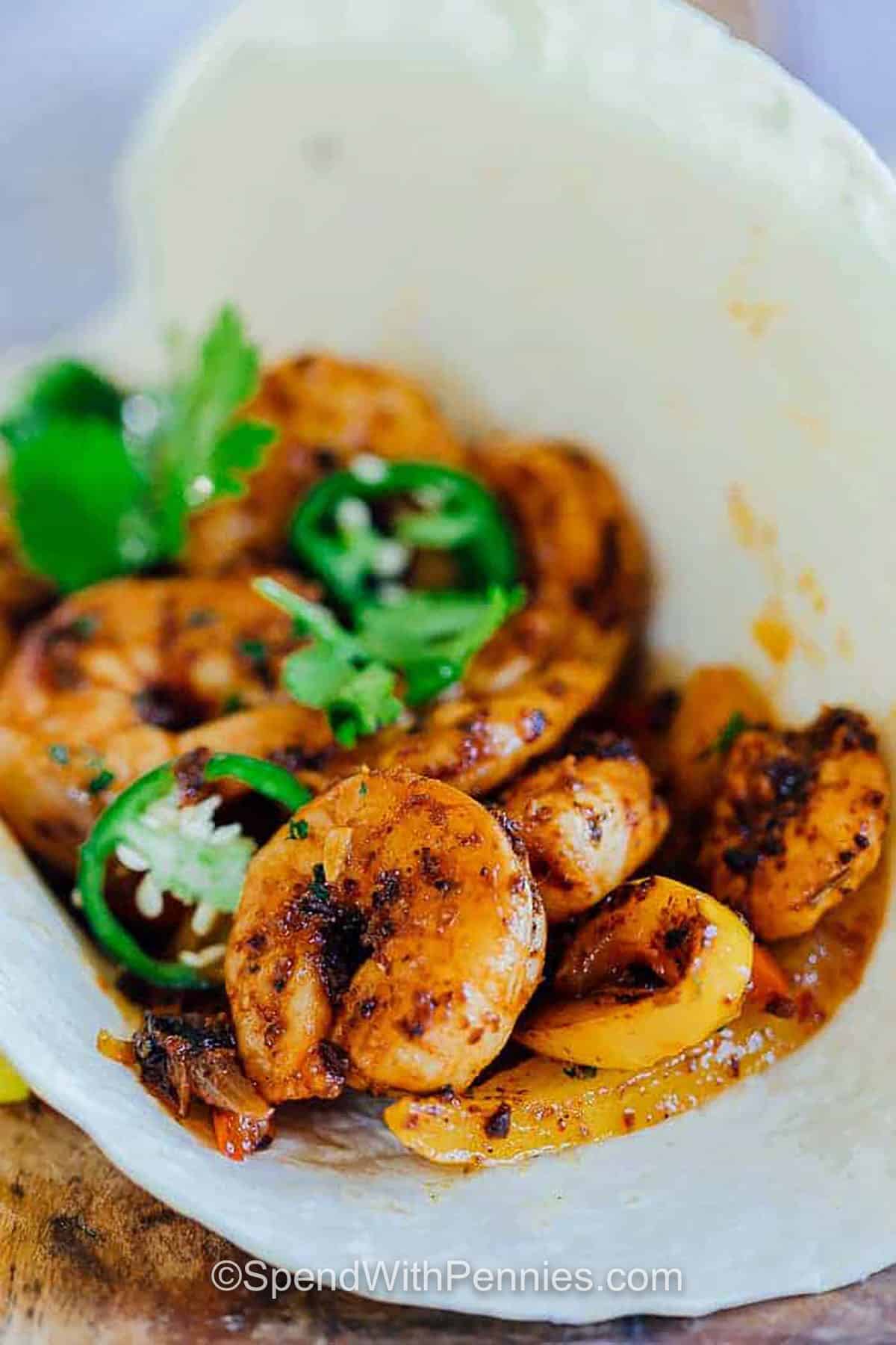 Shrimp fajitas are the perfect mix of tender shrimp, sautéed peppers, and onions tossed in bold chili seasoning. This easy skillet recipe comes together in one pan, making cleanup simple. Serve them in warm tortillas or in a bowl with rice, and don’t forget the toppings like guacamole, cheese, or sour cream. Every bite is fresh, colorful, and packed with flavor that your family will love. #spendwithpennies close up of Shrimp Fajitas