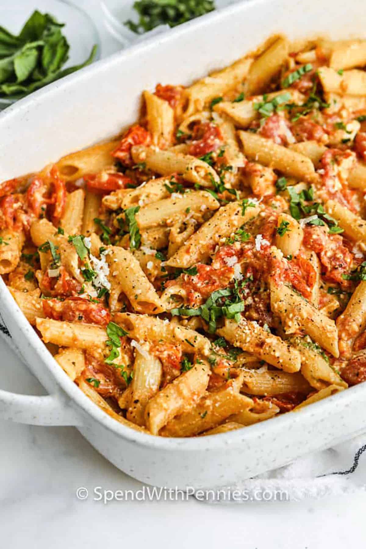 Baked feta pasta is an oven-baked recipe that turns simple ingredients into something special. Juicy cherry tomatoes roast with garlic until bursting with flavor, then bake with a block of cheese until creamy and rich. Toss it all with pasta and you have a one-pan dish that feels elegant yet comforting. This vegetarian pasta bake is packed with roasted flavor and creamy texture, making it perfect for sharing with loved ones. #spendwithpennies Baked Feta Pasta in the casserole dish
