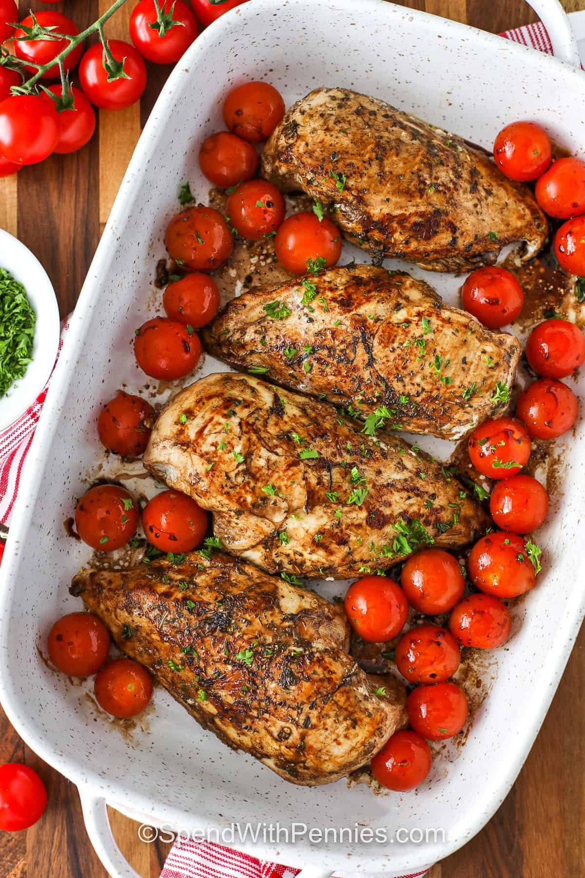 Bruschetta chicken takes tender baked chicken breast and layers it with marinara, cherry tomatoes, and mozzarella. A balsamic-kissed tomato and basil topping brings it all together. This easy Italian-inspired recipe is perfect for serving with pasta, zucchini noodles, or even mashed potatoes for a meal that’s as beautiful looking as it is delicious. #spendwithpennies cooked chicken and tomatoes in the dish to make Bruschetta Chicken