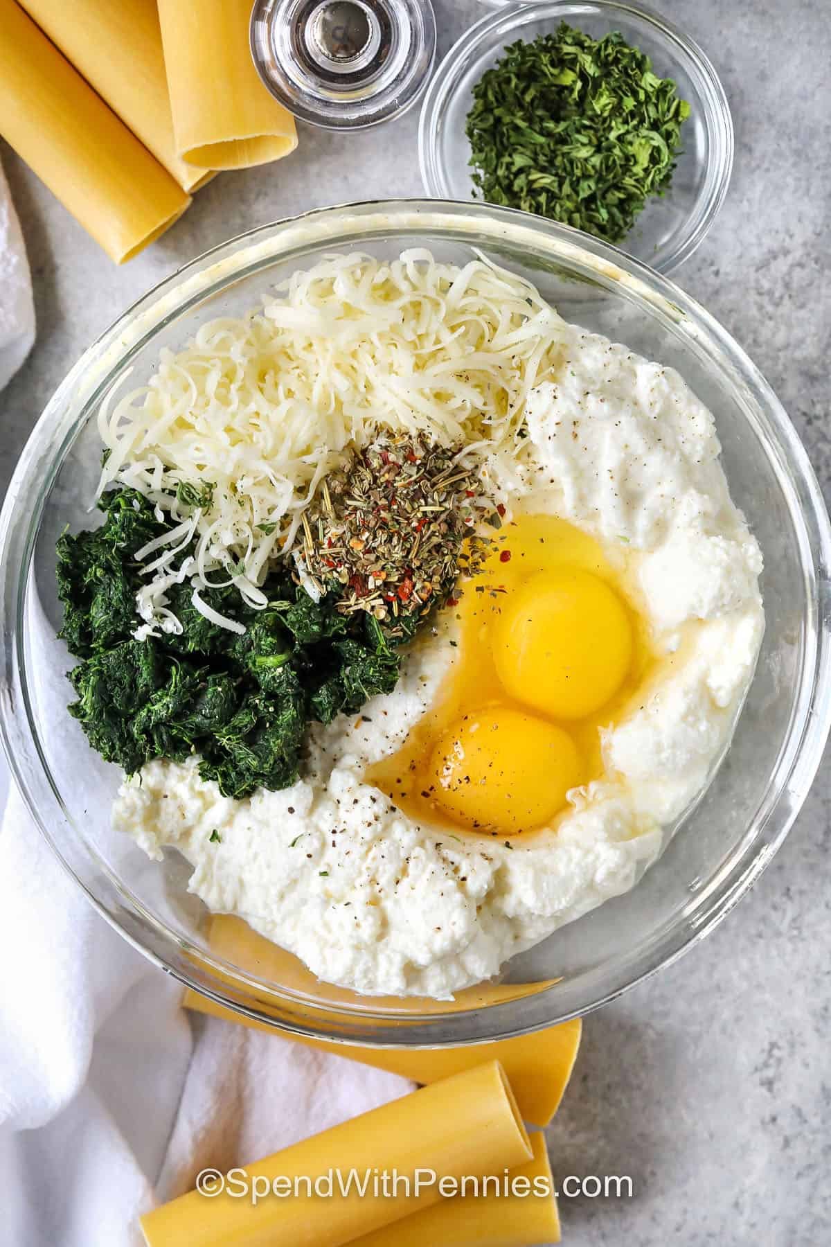adding ingredients to bowl to make filling for Cheese Cannelloni