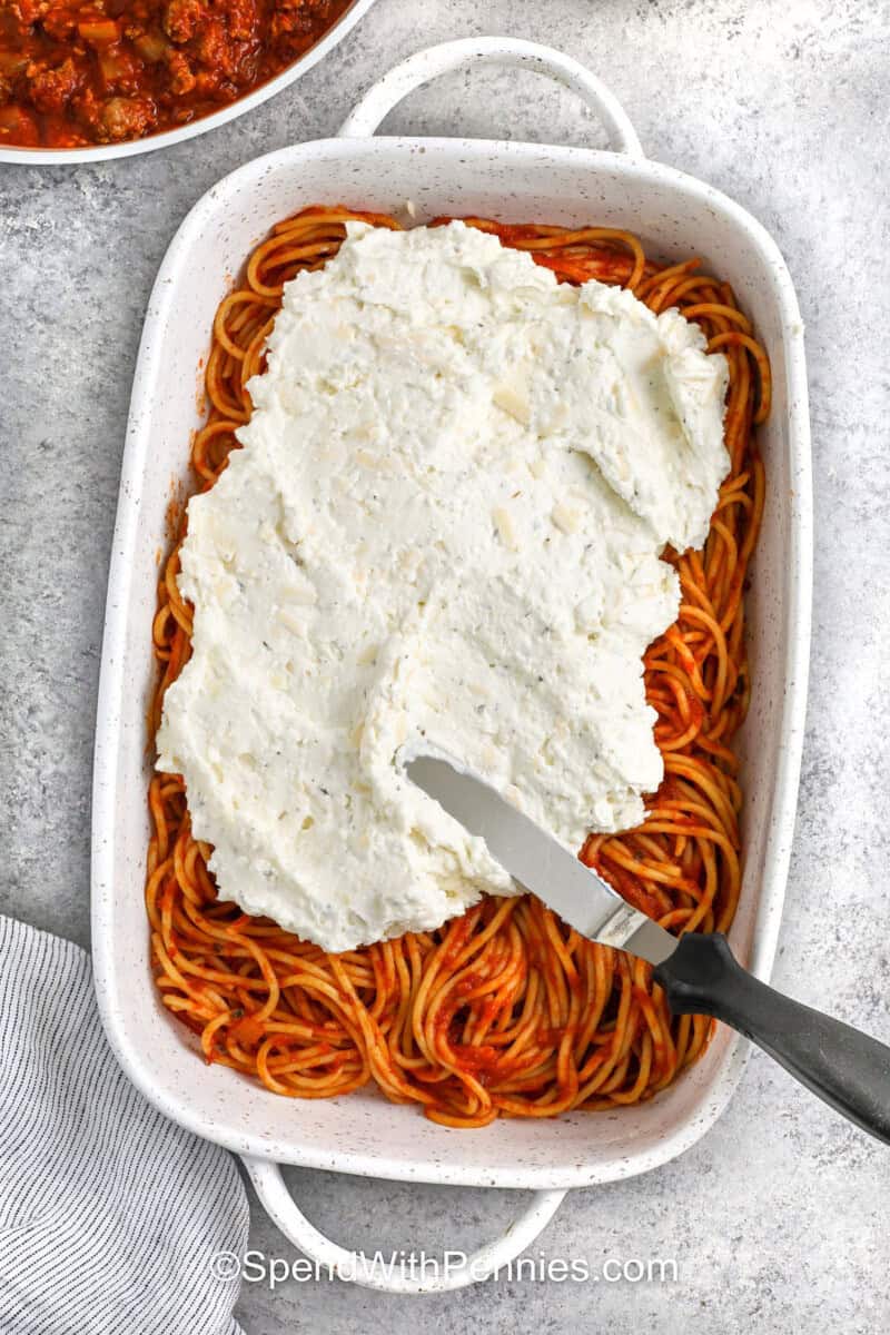 adding cheese mixture on top of spaghetti and sauce