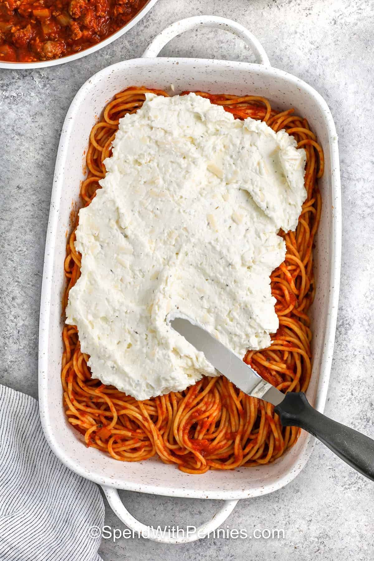 adding cheese mixture on top of spaghetti and sauce
