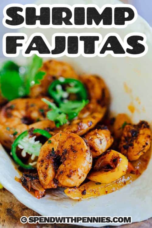 These shrimp fajitas are loaded with tender shrimp, colorful bell peppers, and onions, all tossed in a smoky homemade seasoning. This easy recipe comes together in one pan, making cleanup a breeze. Pile the sizzling filling into warm tortillas, then add your favorite toppings like creamy guacamole or fresh salsa. Every bite is full of flavor and bright zest. A simple way to make a fresh and flavorful dinner. #spendwithpennies close up of zesty Shrimp Fajitas with a title