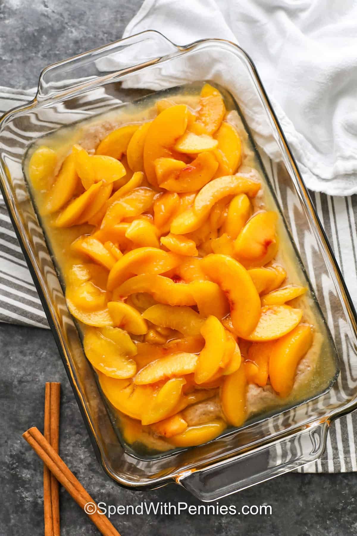adding peaches to crust dough in casserole dish to make Peach Cobbler