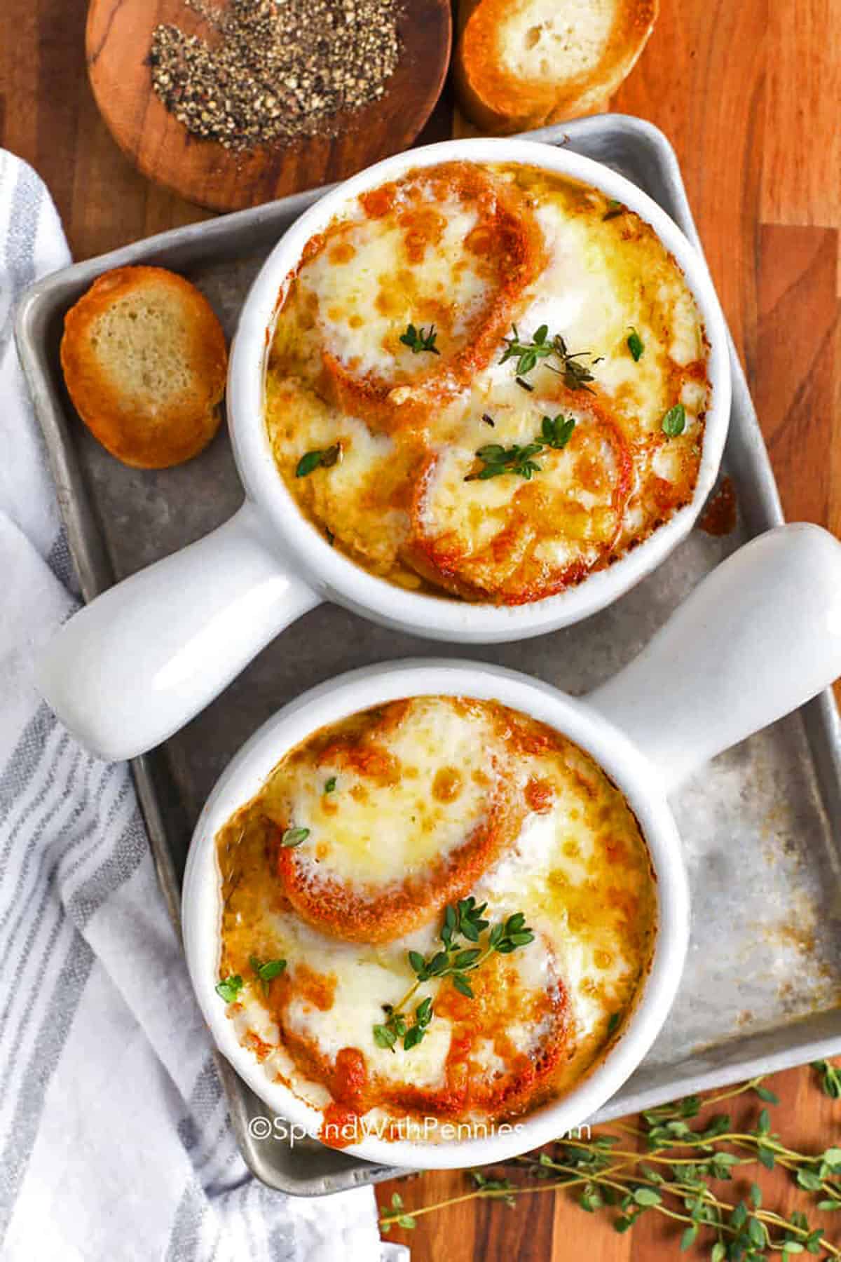 This French onion soup recipe is a cozy mix of caramelized onions, savory beef broth, and golden bubbly cheese. Make this dish in a large pot with a splash of wine and herbs, then finish under the broiler with bread and melty cheese on top. This classic recipe is the best way to turn a handful of ingredients into a warm and comforting meal that is perfect for family dinners or cozy nights at home. #spendwithpennies top view of French Onion Soup in bowls