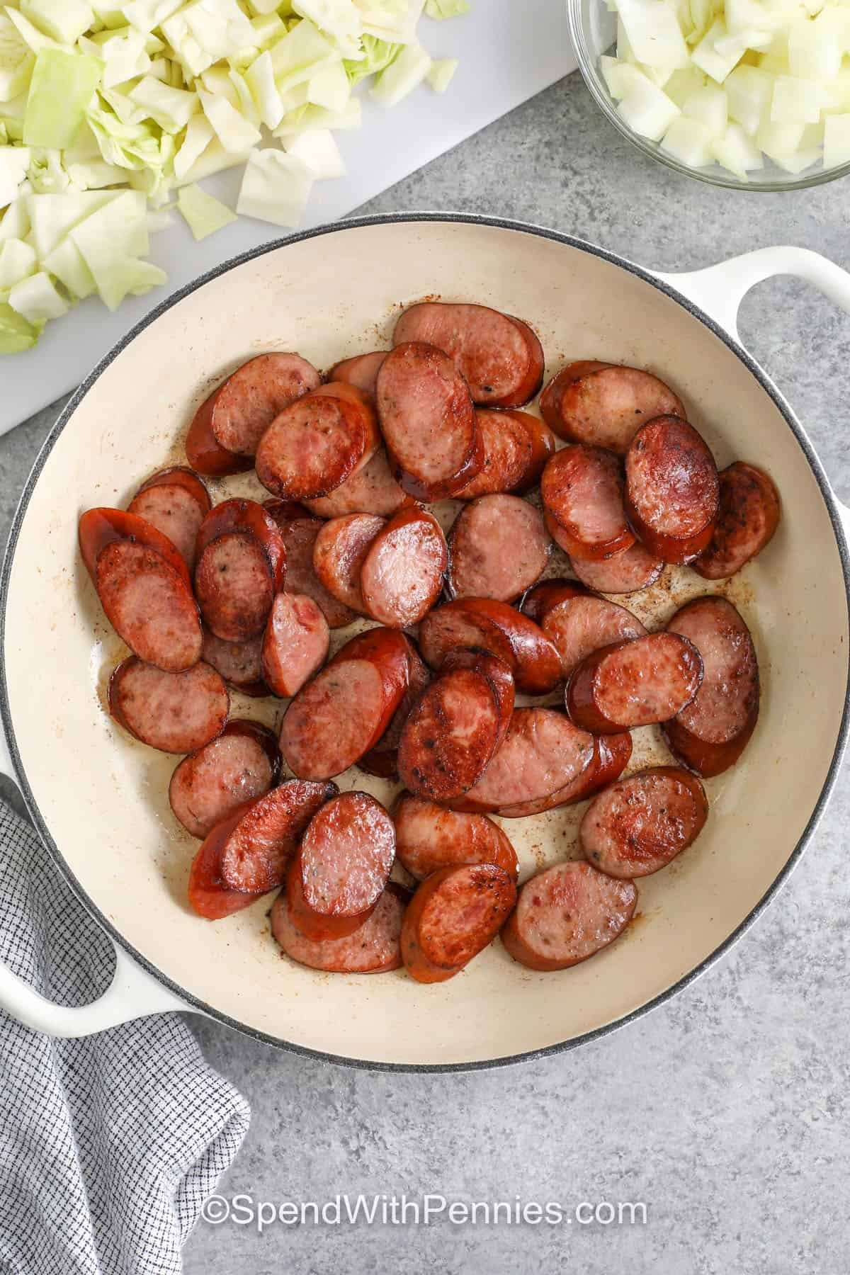 smoked sausage being browned in a skillet