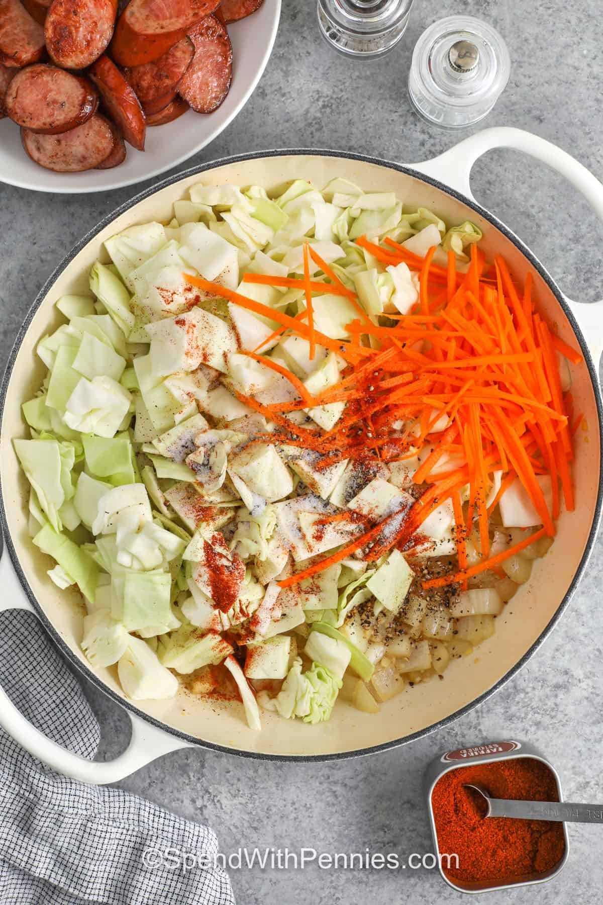 Ingredients to make cabbage and sausage being combined in a skillet