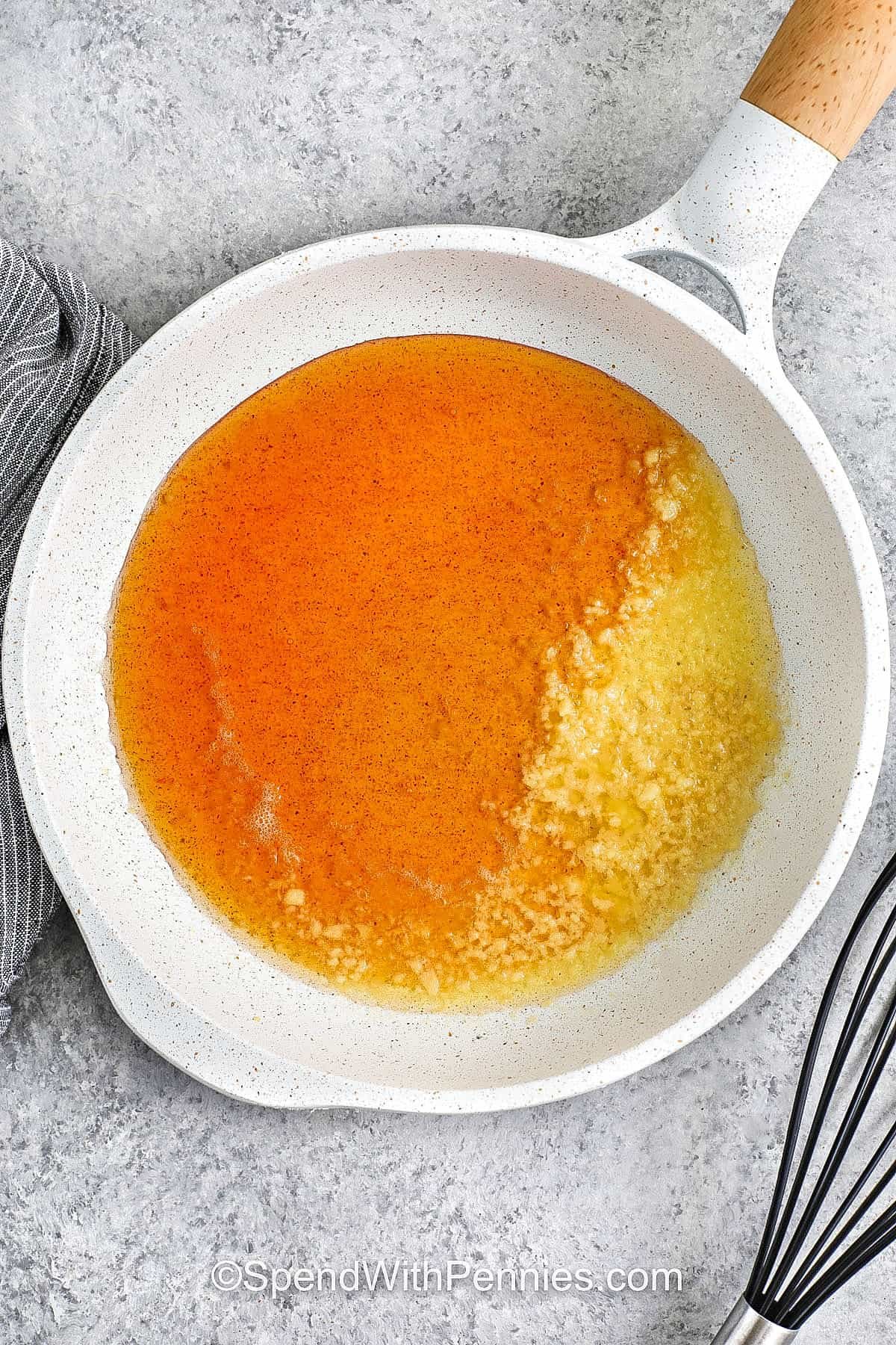 Hot honey chicken is a crave-worthy recipe you’ll want to make again and again. The chicken is seasoned, baked, and glazed with a sauce of hot honey, butter, garlic, and vinegar for the perfect mix of sweet and spicy. Enjoy it as a main dish, or slice it into tenders for serving in place of chicken wings. It’s also delicious tucked into a sandwich or layered over a bowl of greens and grains. #spendwithpennies adding ingredients to pan to make Hot Honey for Hot Honey Chicken