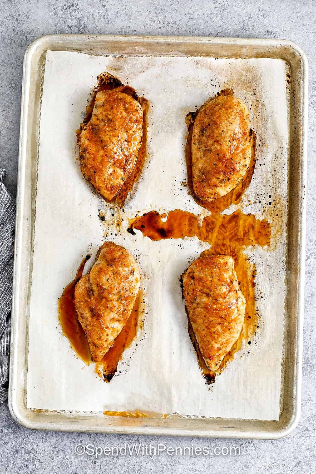 Hot honey chicken combines savory spices with a sweet and spicy glaze that’s simply irresistible. Each chicken breast is seasoned with paprika, onion powder, and thyme before being coated in a garlic butter sauce with hot honey. The result is juicy, flavorful chicken that can be sliced into tenders, layered into a sandwich, or served over a fresh rice bowl. This recipe brings big flavor to the table. #spendwithpennies baked Hot Honey Chicken on a sheet pan