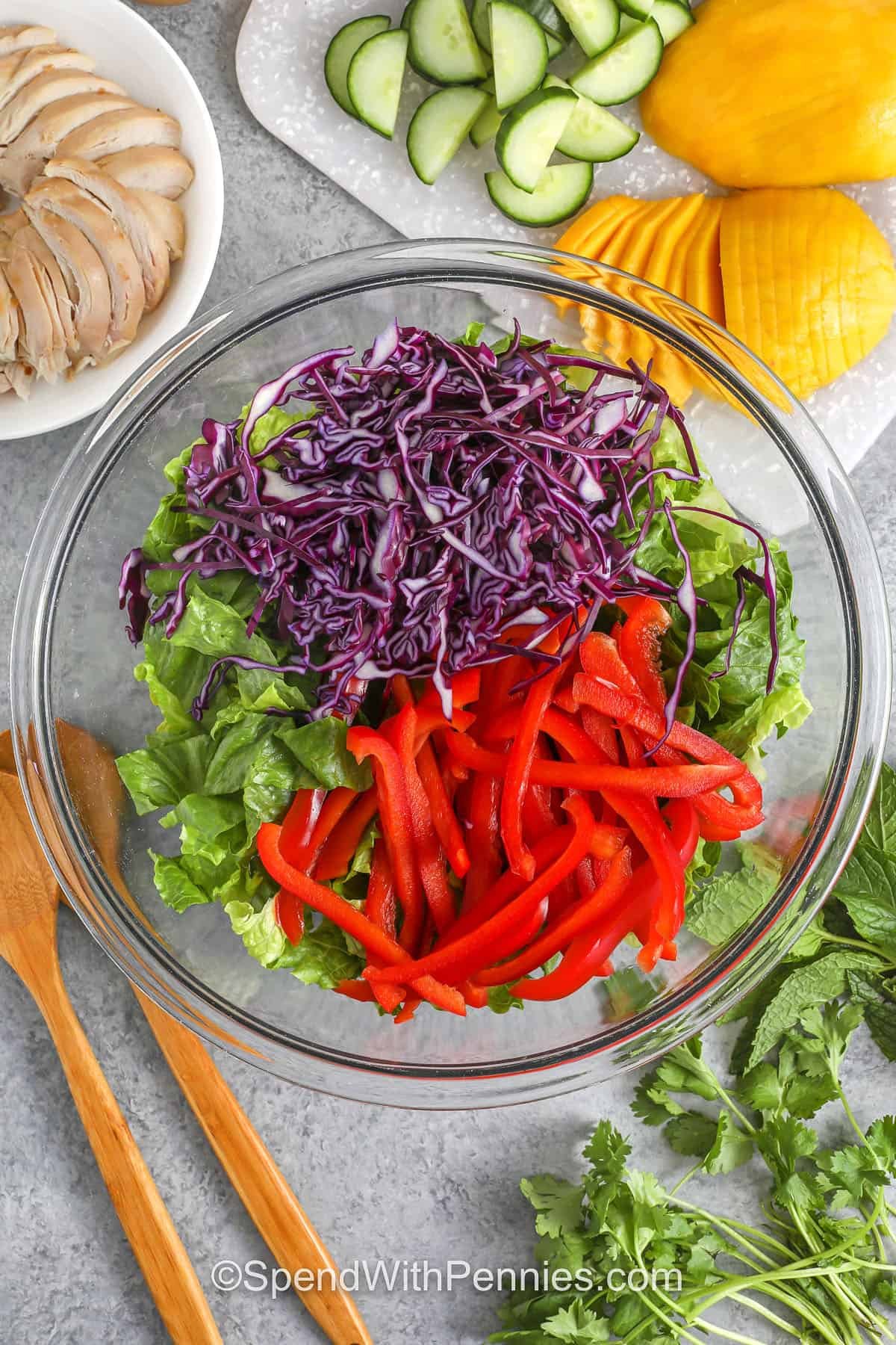 adding veggies to lettuce to make Mango Chicken Salad