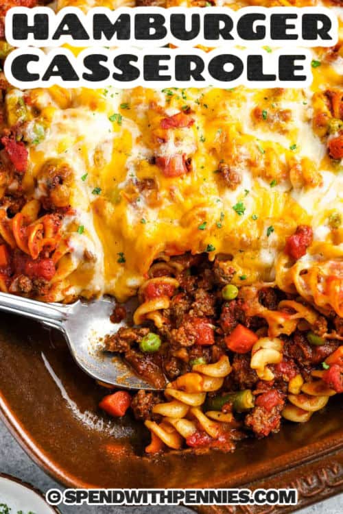 Hamburger casserole is a comforting recipe that brings together seasoned beef, pasta, and veggies in a rich sauce. Swap or add rice or noodles if you like, but here we use rotini. The melted cheese on top is irresistible. It’s not quite a soup, but saucy enough to feel cozy. Simple, easy, and satisfying, making it perfect for weeknight dinners that taste like a warm hug. #spendwithpennies close up of Hamburger Casserole in the casserole dish with a spoon and title