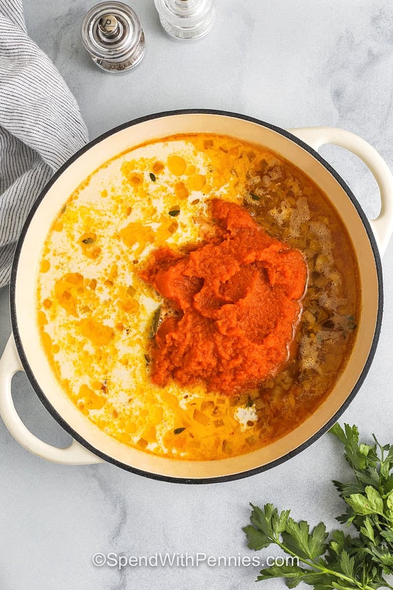 adding pumpkin and whipping cream to pot to make Pumpkin Soup