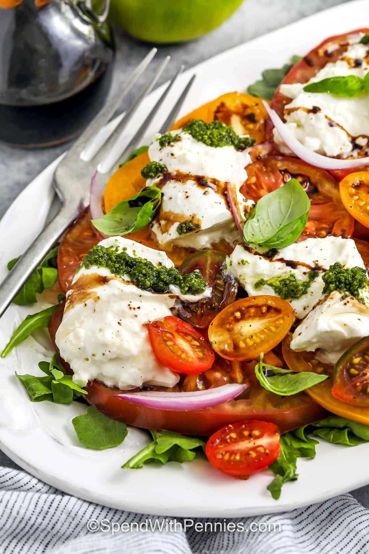close up of Tomato Burrata Salad on a plate with a fork