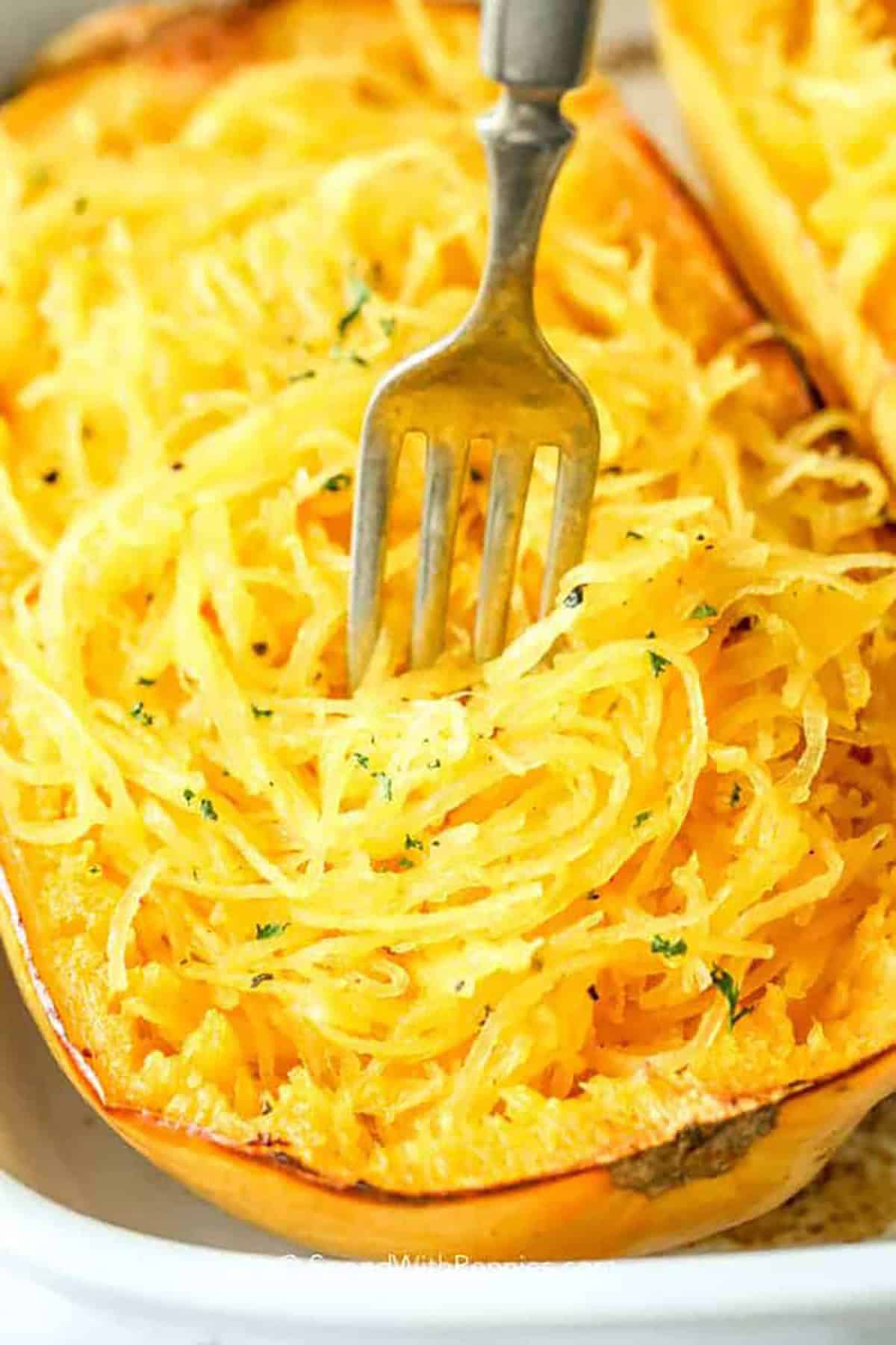 Baked spaghetti squash is a delicious twist on pasta – it's healthier and easy to make! Just roast it in the oven to bring out that natural sweetness, and you've got a low-carb noodle alternative. Top it with sauce, herbs, and cheese, or get creative with stir-fries for a tasty meal! #bakedspaghettisquash #lowcarb #baked #spendwithpennies  closeup of a fork shredding baked spaghetti squash