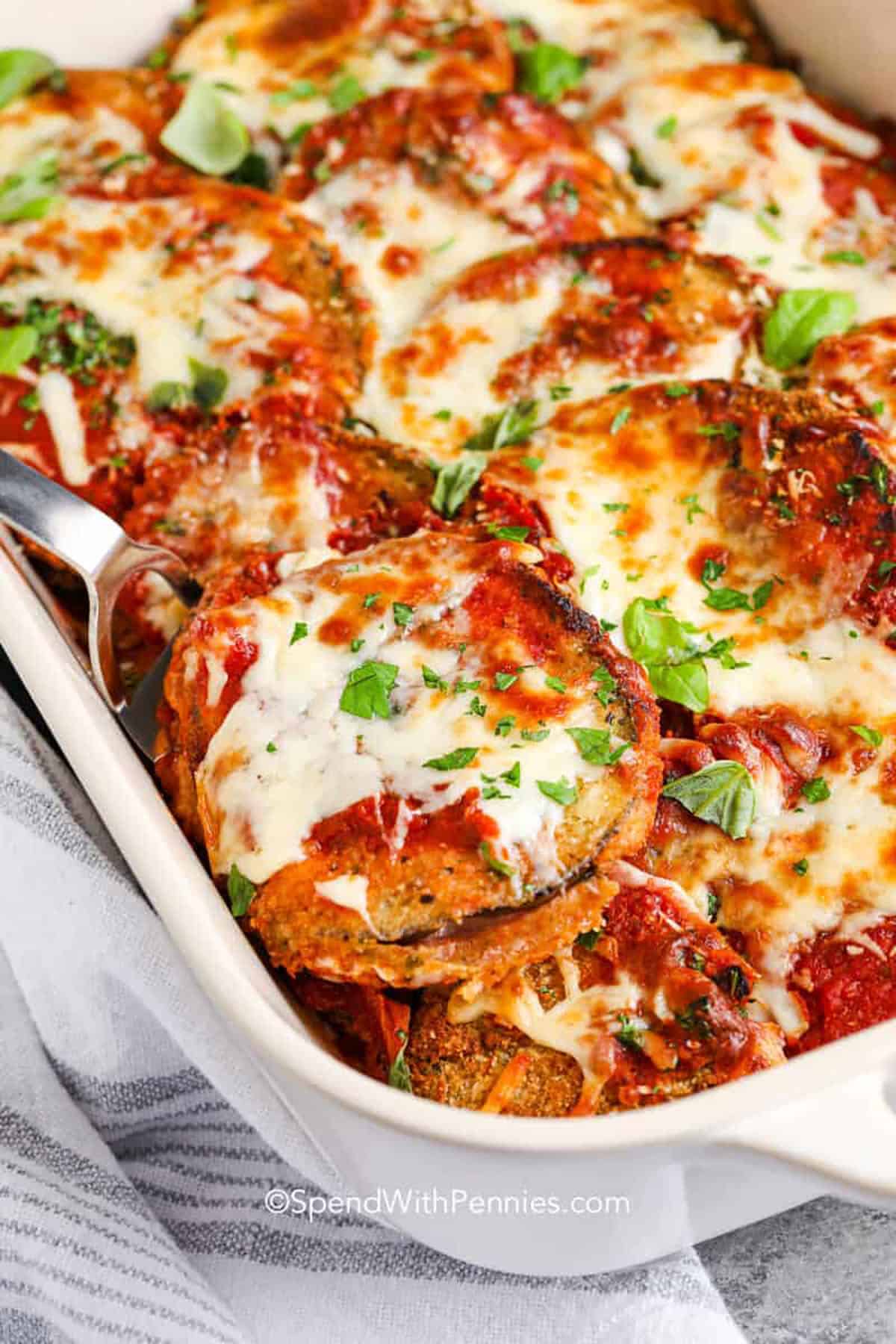Eggplant parmesan brings cheesy Italian flavors to the table with every bite. In this recipe, tender slices of eggplant are breaded, cooked golden, and layered with marinara, Parmesan, and mozzarella. This baked dish is hearty, satisfying, and such a great vegetarian alternative to chicken parmesan. With layers of sauce and cheese and crispy breaded eggplant, it’s easy to make and feels both comforting and healthy. Serve with salad or pasta for a complete dinner. #spendwithpennies Eggplant Parmesan in a casserole dish
