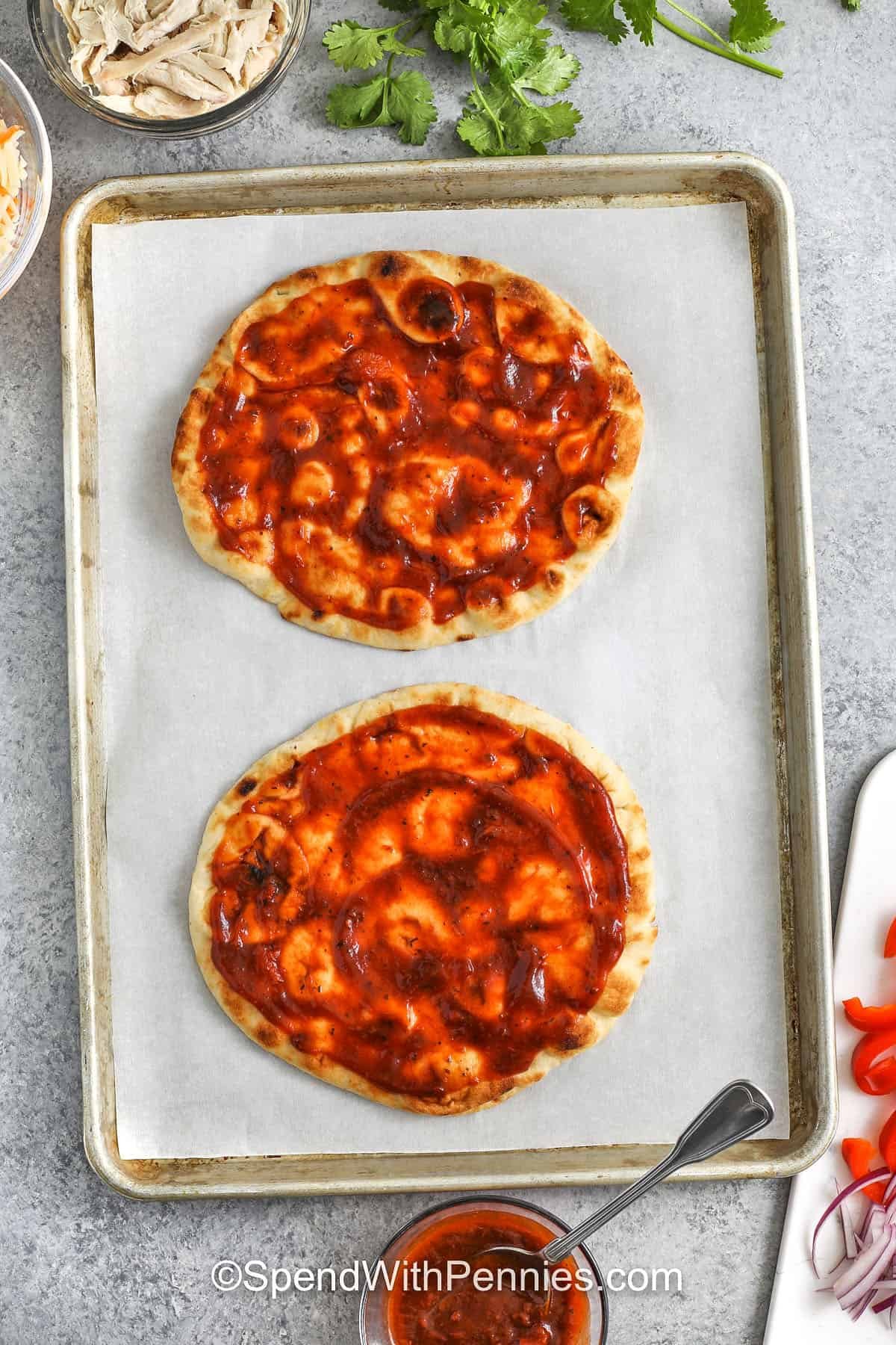Craving bold smoky flavor without firing up the grill? This BBQ chicken flatbread has you covered. Layered with a zesty blend of BBQ and pizza sauce, tender chicken, sweet red bell peppers, and gooey melted cheese on a crisp naan base, it’s everything you love made lighter. Lower in calories and big on taste, it's a quick, satisfying option that fits right into your healthy routine. #spendwithpennies adding sauce to pizza dough to make BBQ Chicken Flatbread